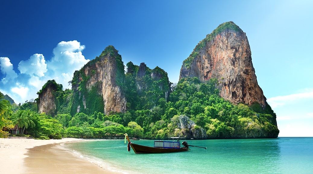 Empty boat floating on turquoise sea water with tall rock formation in the background